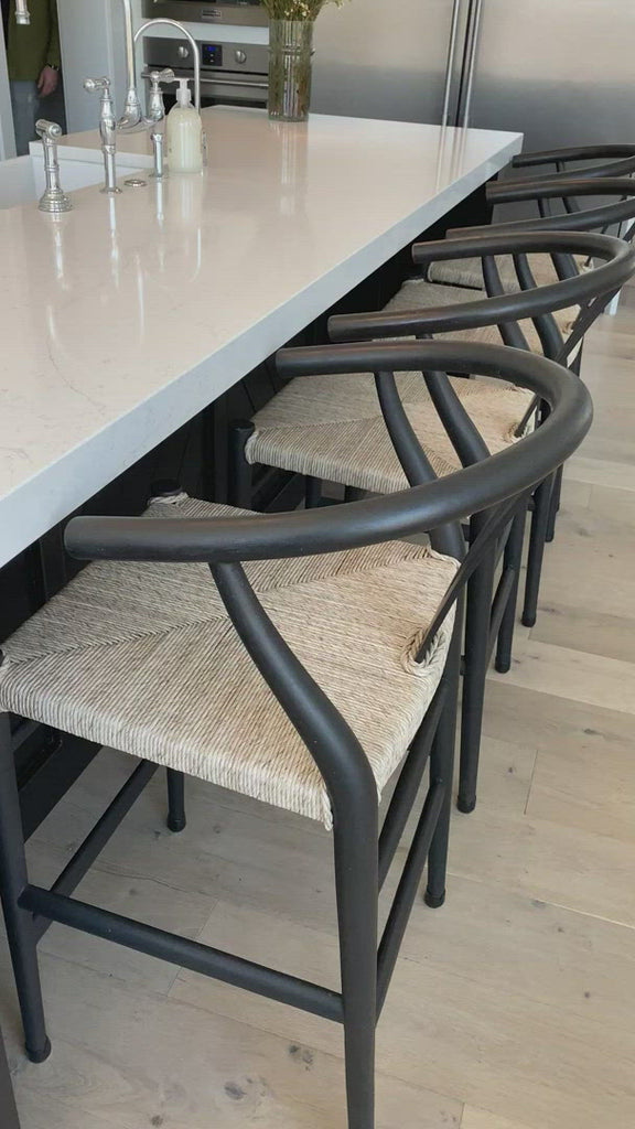 Modern curves redefine the classic wishbone-style of this Muestra Black Teak Counter + Bar Stool. Vintage white all-weather wicker is woven for a dose of fresh texture within weathered grey teak framing. Cover or store indoors during inclement weather and when not in use.